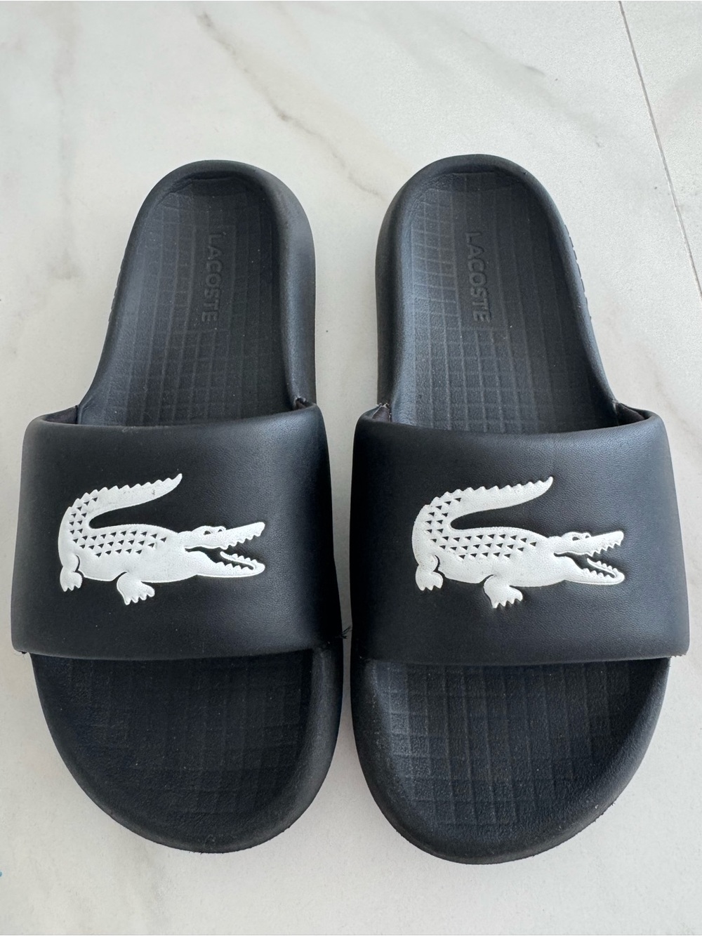 Lacoste Black Slides with White Croc Logo runs small. Size 8 but fits like 7